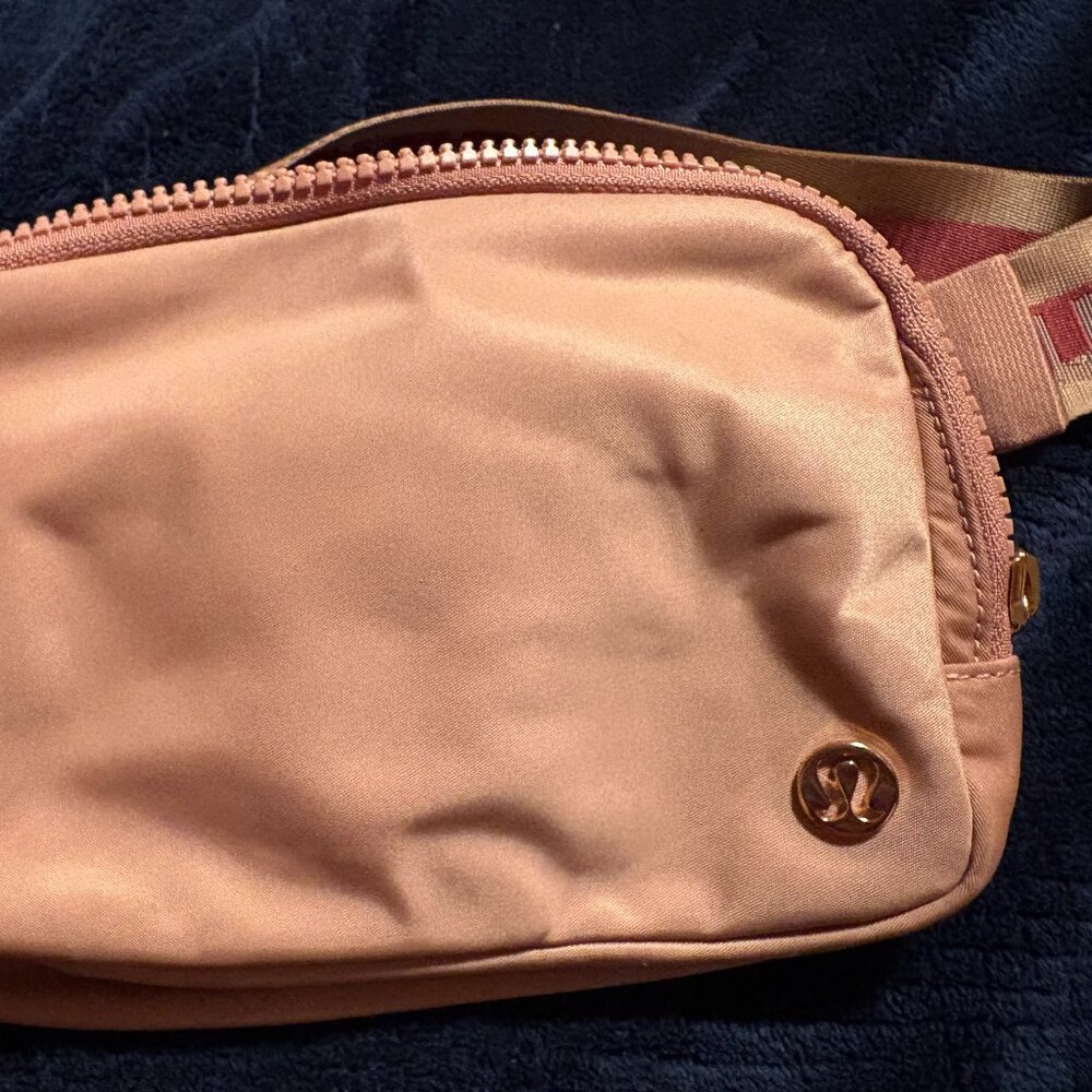 Lululemon Belt Bag 1L Wordmark in medium pink (forgot name) with rose gold.